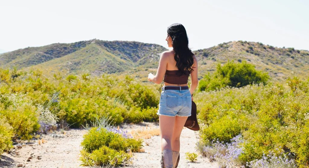 A person hiking on a short trail with minimal shade on a sunny spring day