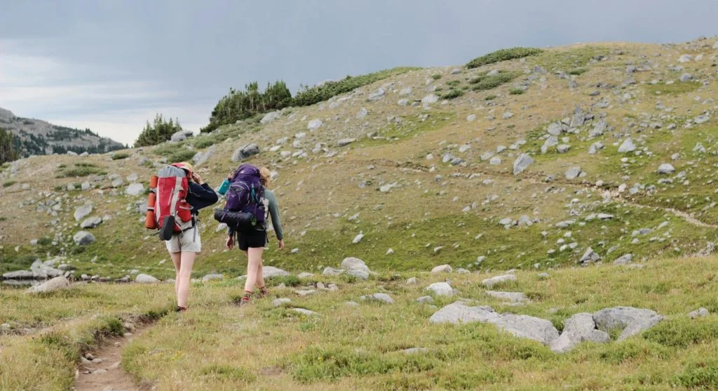 hiker using wide shoulder on narrow trail