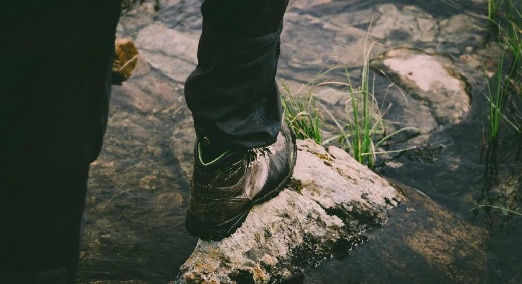 Person hiking on a trail with a sign of a slip