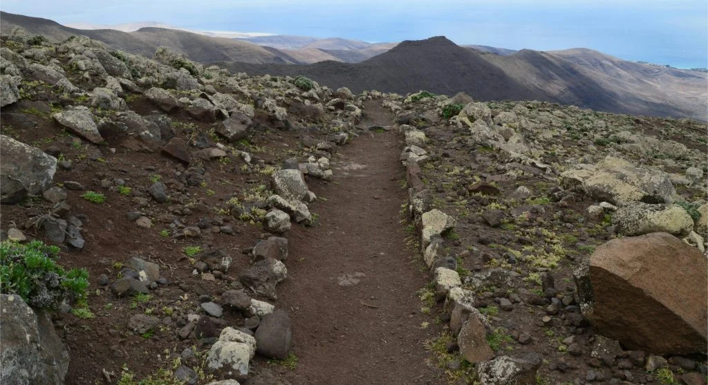 hiker steps from rock to loose dirt trail