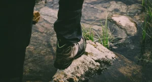 hiker stepping from rock to dirt trail